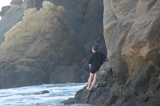 Woman on the rocks, contemplating the ocean